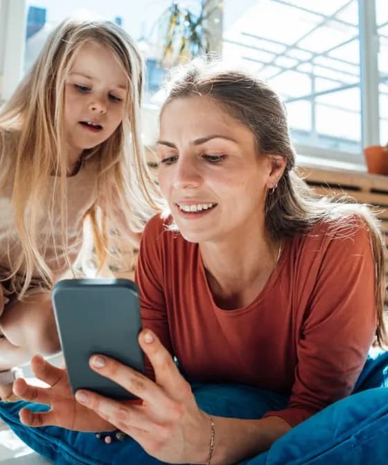 Mother sharing phone with daughter