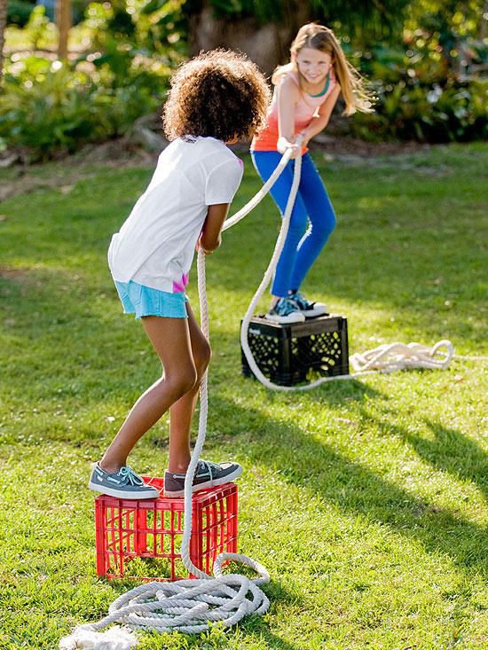 Kids playing tug of war on crates in backyard