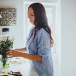Housekeeper arranging flowers in vase in kitchen