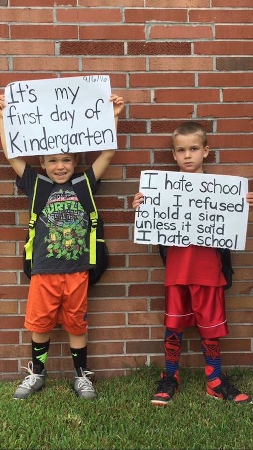 First day of school meme: One boy holding a sign It's my first day of kindergarten. The second boy holding a sign I hate school and I refused to hold a sign unless it said I hate school. 