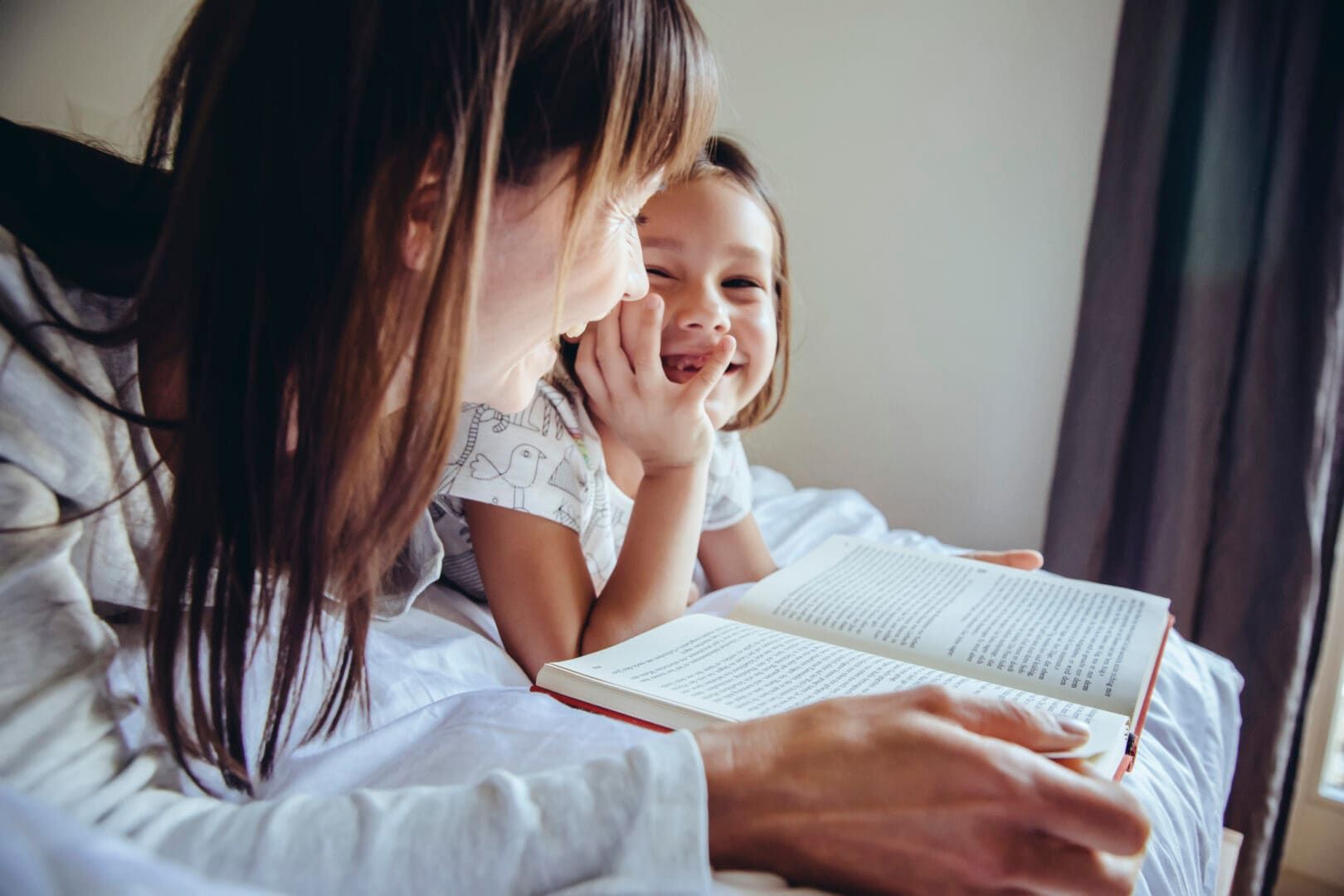 Nanny and child reading book and laughing together