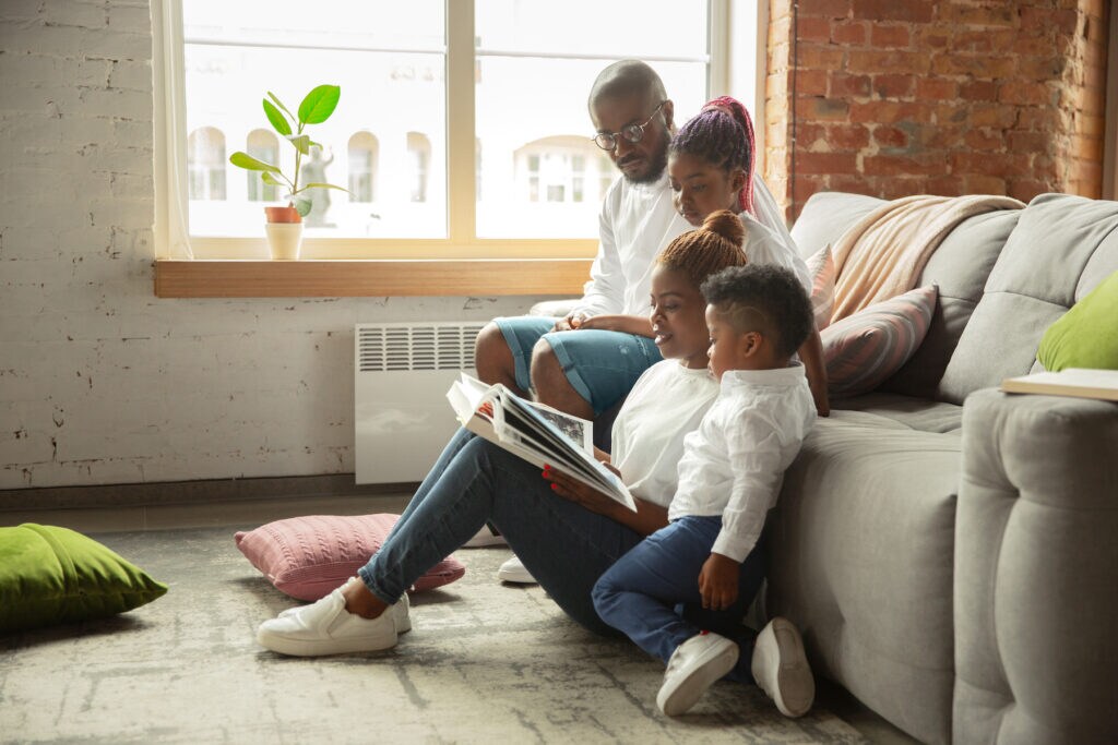 Young Black family reading History book together at home
