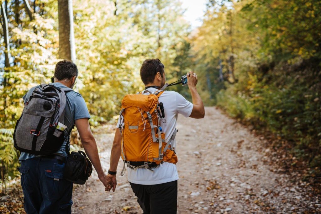 Couple holding hands and hiking in forest on beautiful sunny day date