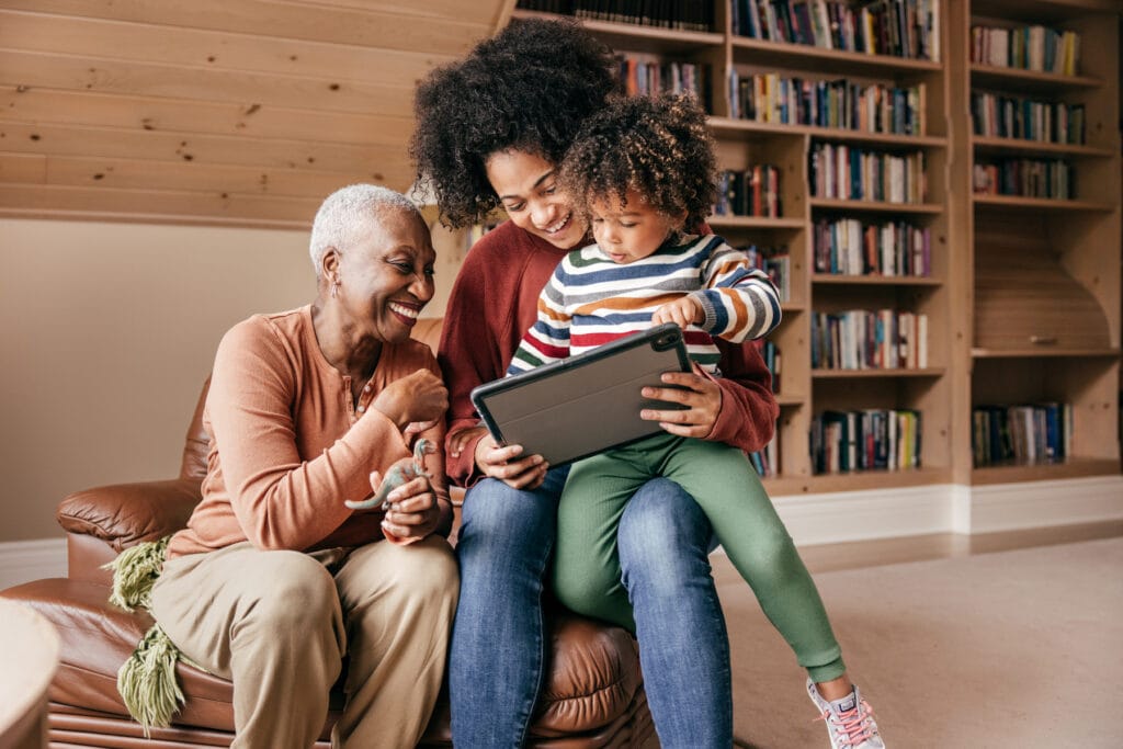 Three generation family watching movie on a tablet and laughing together