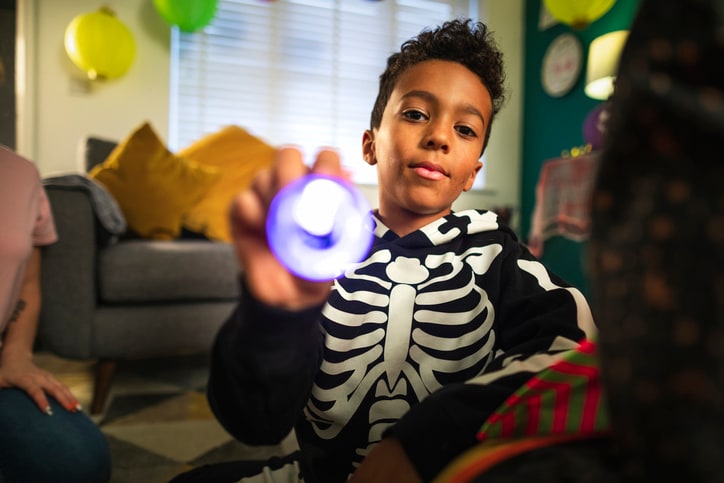 Boy dressed up as skeleton with flashlight on Halloween